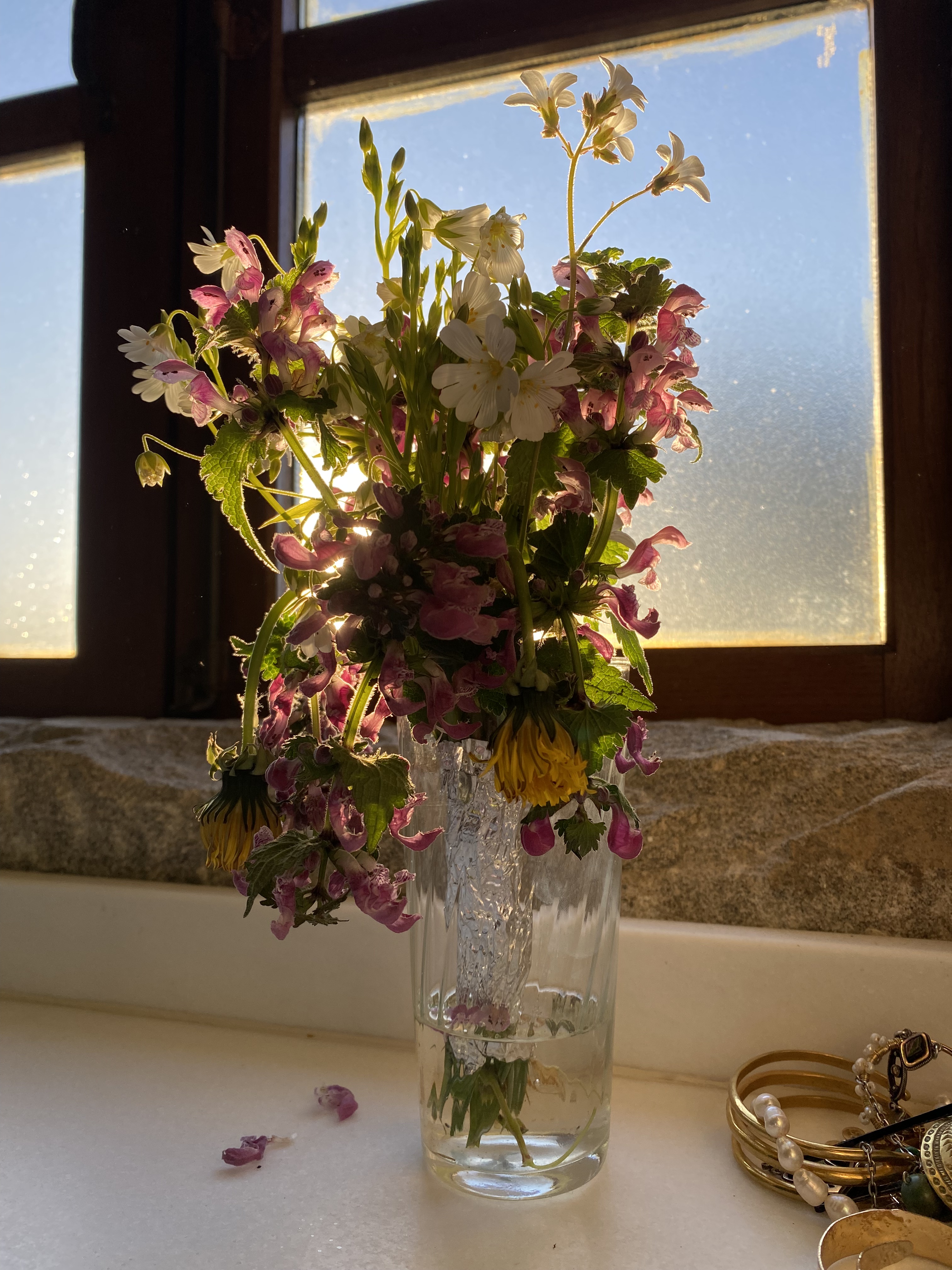 jarrón de cristal transparente con un ramo de flores silvestres marchitándose.