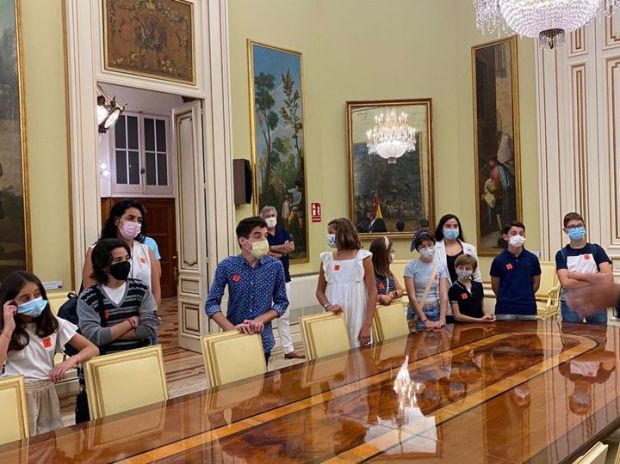 Un grupo de chicos y chicas de pie alrededor de un salón muy suntuoso en el Ministerio de Educación de España