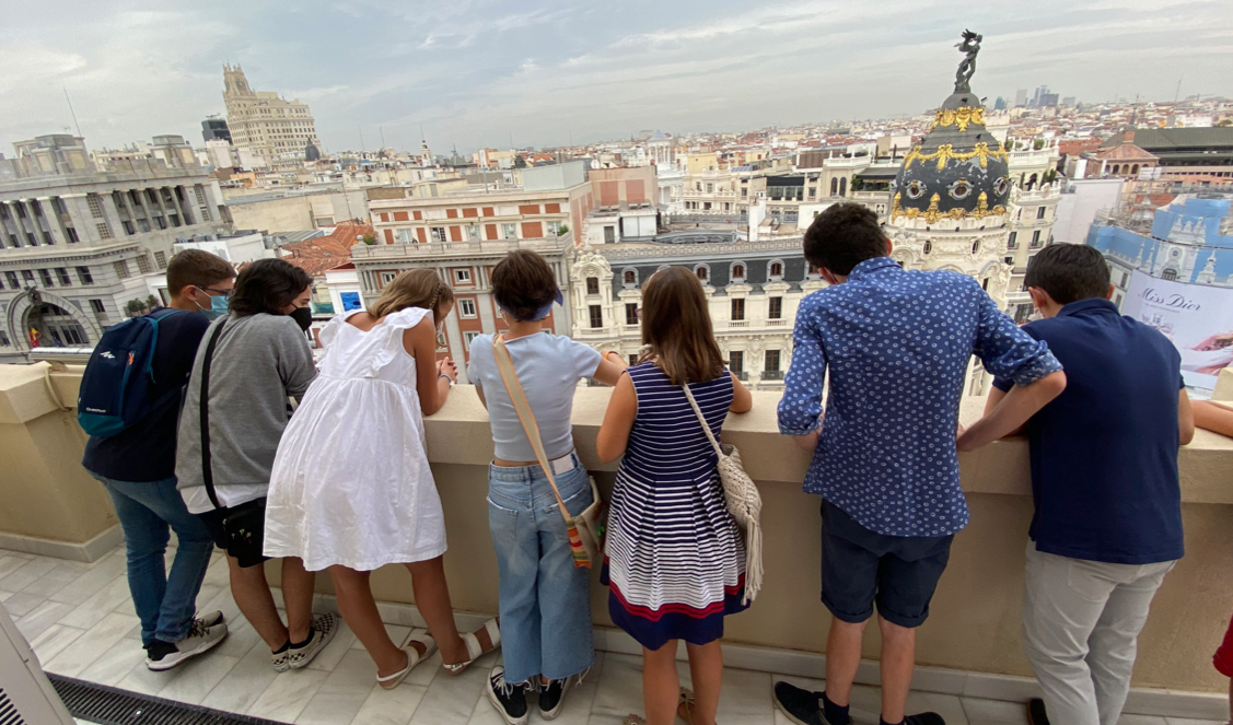 Foto tomada de espaldas de un grupo de chicos y chicas asomados y mirando hacia abajo en una de las terrazas del ministerio