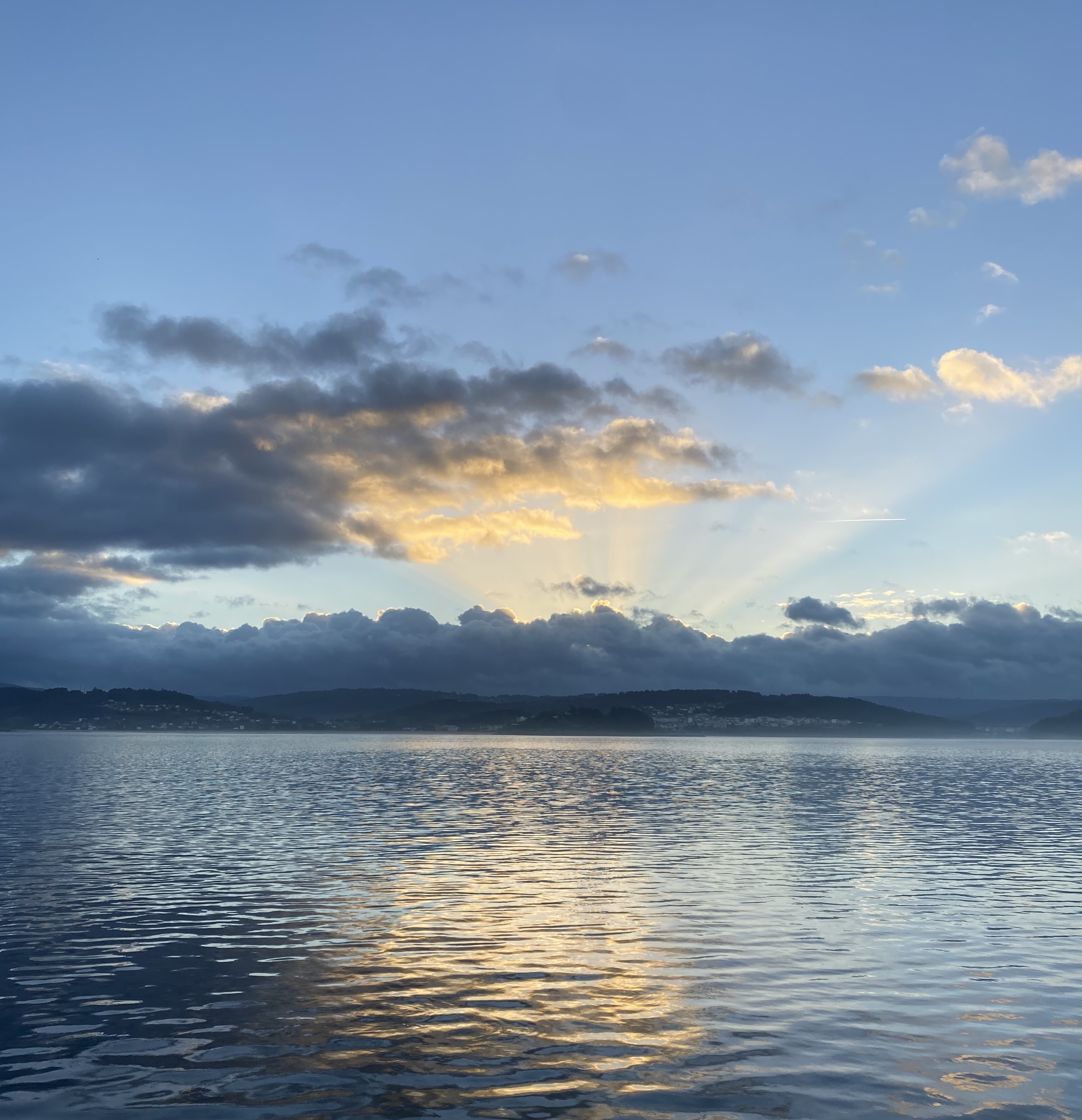 Foto de una amanecer sobre el mar. Se aprecia asomando el sol entre la bruma baja, la parte superior del cielo es de un azul intenso