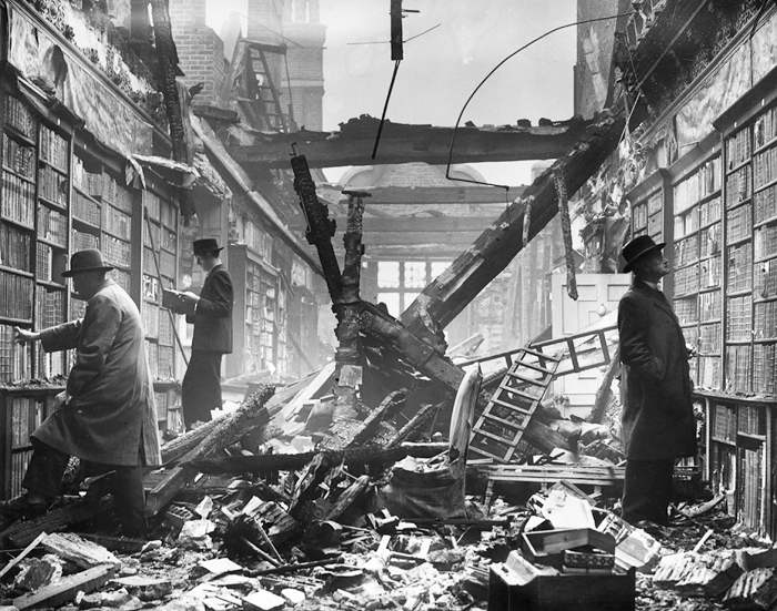 Fotografía en blanco y negro tomada en la librería Holland House de Londres en septiembre de 1940. Un bombardeo alemán la había destruido la noche anterior y, sin embargo, había dejado intactas las paredes con las estanterías repletas de libros perfectamente ordenados. La imagen muestra a tres hombres elegantemente vestidos curioseando entre los estantes.