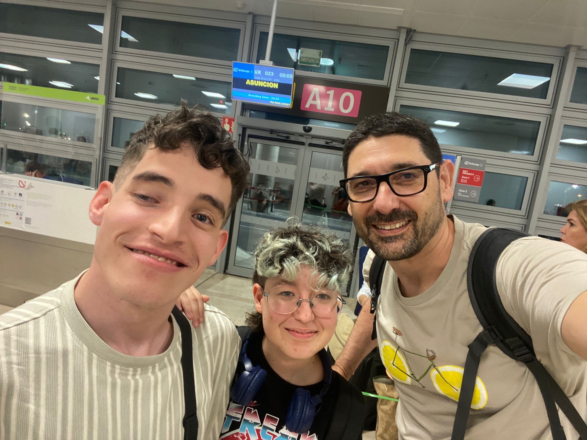 Antón, Nacho y Malena posan sonrientes delante de la puerta de embarque para Asunción